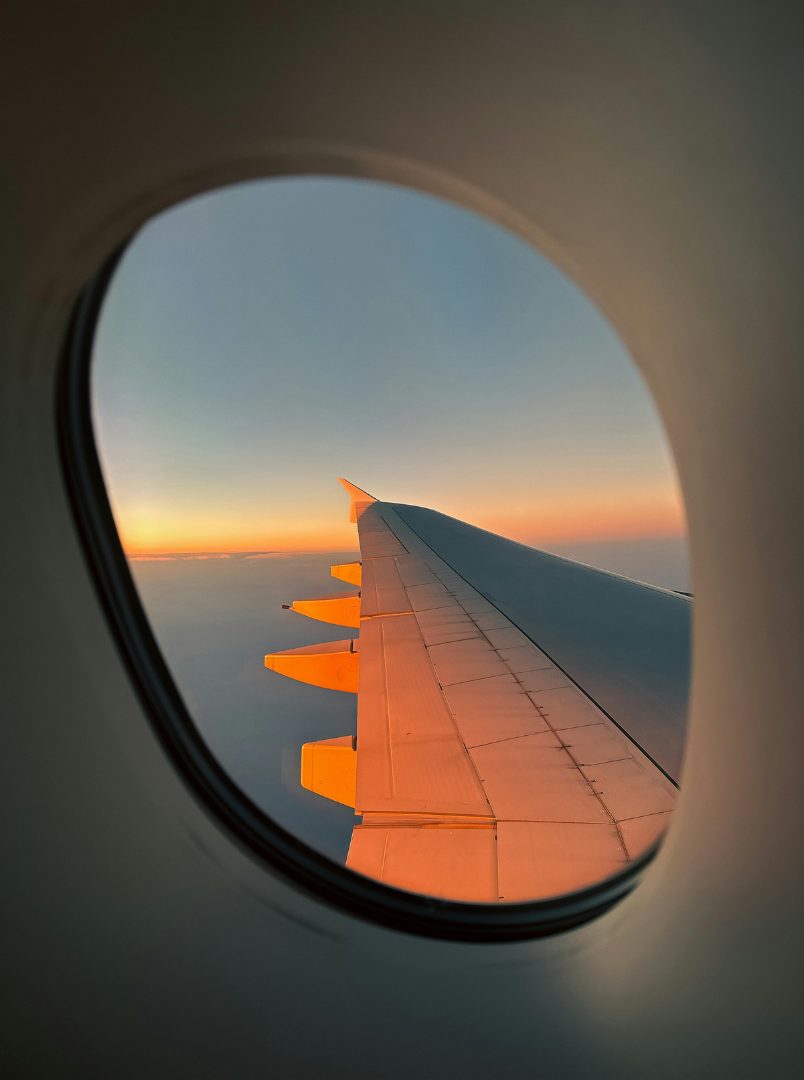 Aircraft wing at sunset through a window